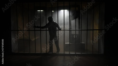Execution concept. Death penalty guillotine miniature inside old prison. Old prison bars cell lock. Man inside jail. Horror view of Guillotine scale model in the dark