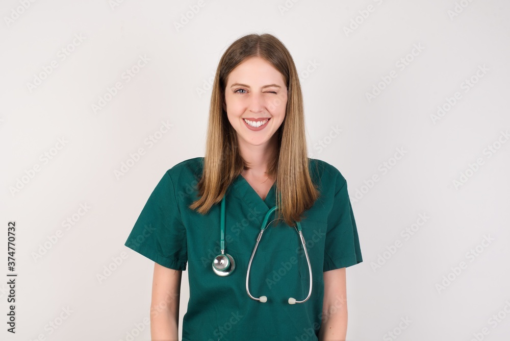 Coquettish Female doctor wearing a green scrubs and stethoscope, smiling happily, blinking at camera in a playful manner, flirting with you. Human facial expressions and emotions Coquettish Female doctor wearing a green scrubs and stethoscope, smiling happily, blinking at camera in a playful manner, flirting with you. Human facial expressions and emotions
