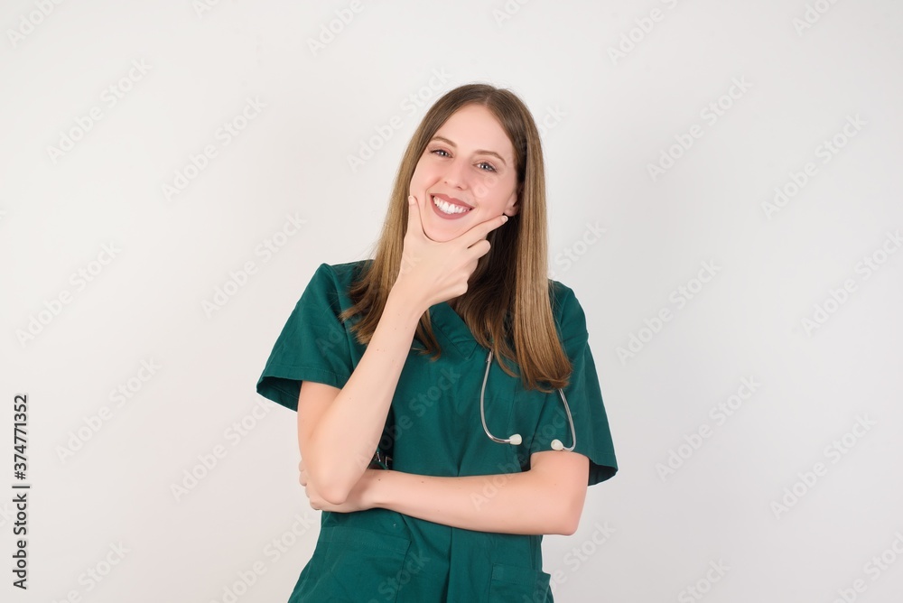 Female doctor wearing a green scrubs and stethoscope looking confident at the camera smiling with crossed arms and hand raised on chin. Thinking positive. Female doctor wearing a green scrubs and stethoscope looking confident at the camera smiling with crossed arms and hand raised on chin. Thinking positive.