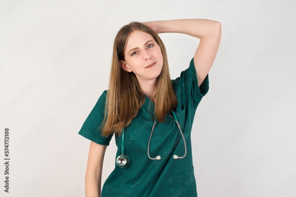 Female doctor wearing a green scrubs and stethoscope being confused and wonders about something. Holding hand on her head, uncertain with doubt. Pensive concept. Female doctor wearing a green scrubs and stethoscope being confused and wonders about something. Holding hand on her head, uncertain with doubt. Pensive concept.