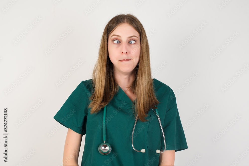 Female doctor wearing a green scrubs and stethoscope making grimace and crazy face, screaming out of control, funny lunatic expressing freedom and wild. Female doctor wearing a green scrubs and stethoscope making grimace and crazy face, screaming out of control, funny lunatic expressing freedom and wild.