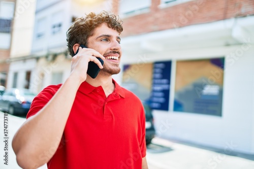 Young handsome caucasian man smiling happy. Having conversation talking on the smartphone at city. © Krakenimages.com