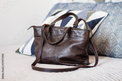 Woman brown leather bag on the gray sofa, female accessory.