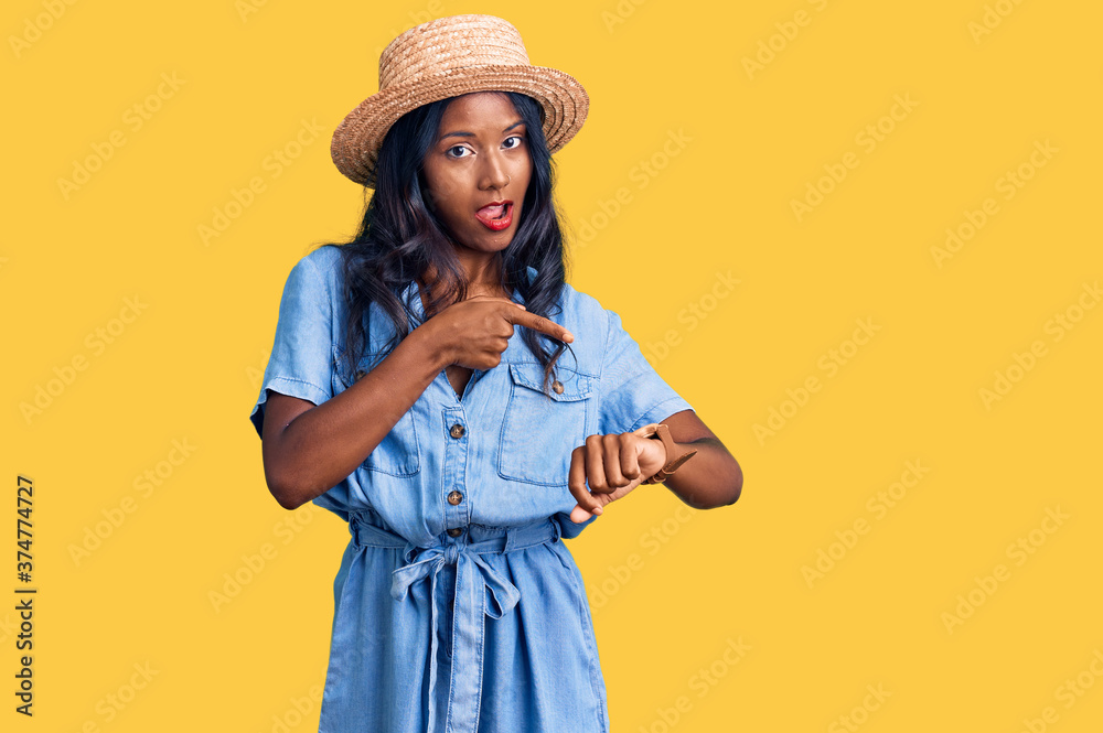 Young indian girl wearing summer hat in hurry pointing to watch time, impatience, upset and angry for deadline delay Young indian girl wearing summer hat in hurry pointing to watch time, impatience, upset and angry for deadline delay
