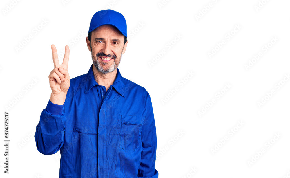 Middle age handsome man wearing mechanic uniform showing and pointing up with fingers number two while smiling confident and happy.