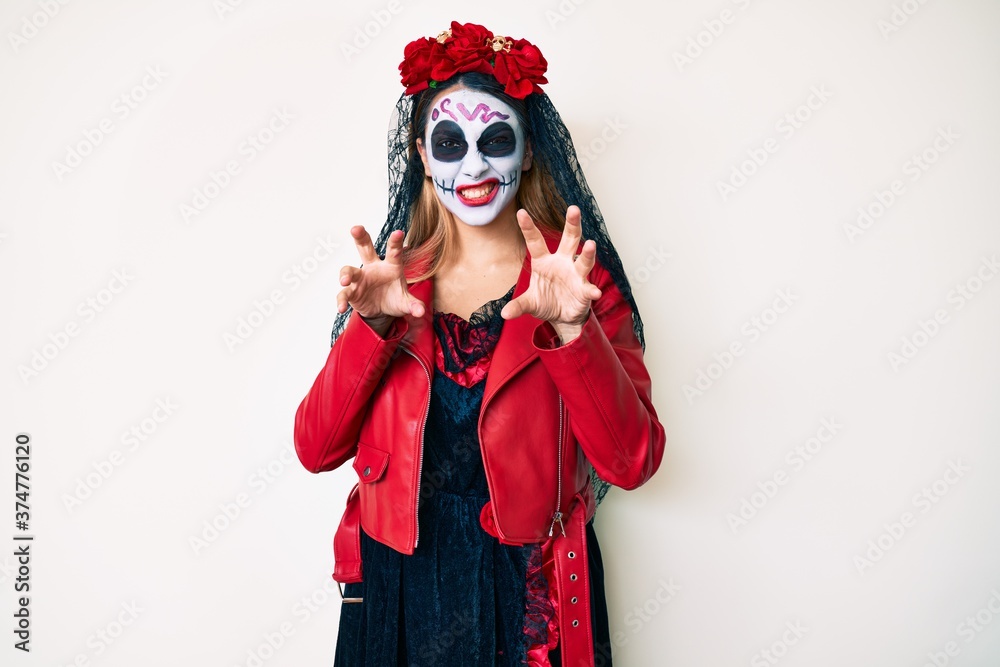 Woman wearing day of the dead costume over white smiling funny doing claw gesture as cat, aggressive and sexy expression Woman wearing day of the dead costume over white smiling funny doing claw gesture as cat, aggressive and sexy expression