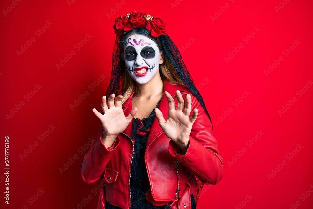 Woman wearing day of the dead costume over red disgusted expression, displeased and fearful doing disgust face because aversion reaction. with hands raised Woman wearing day of the dead costume over red disgusted expression, displeased and fearful doing disgust face because aversion reaction. with hands raised