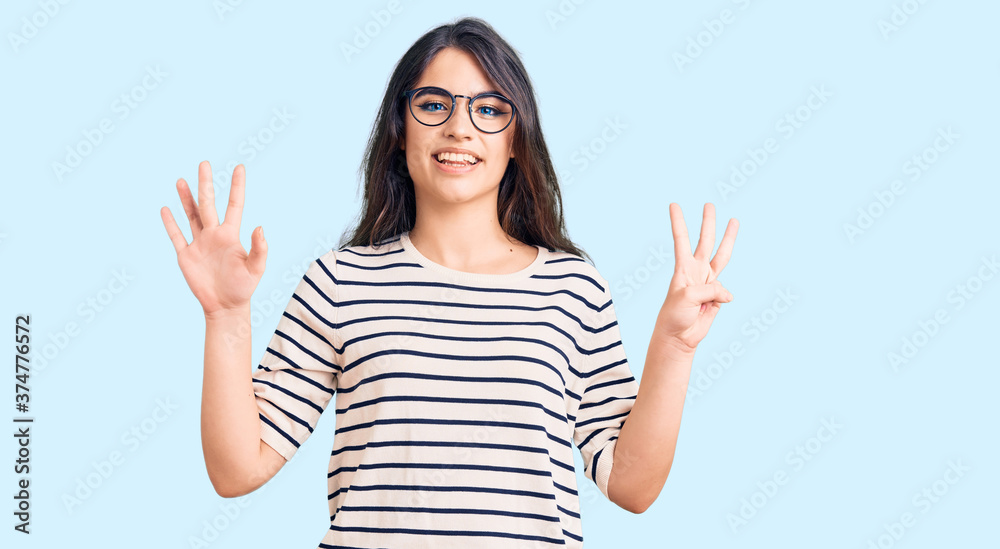 Brunette teenager girl wearing casual clothes and glasses showing and pointing up with fingers number eight while smiling confident and happy. Brunette teenager girl wearing casual clothes and glasses showing and pointing up with fingers number eight while smiling confident and happy.