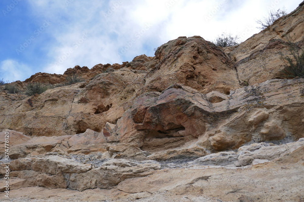 Rocky cliff with jagged sandstone and blue sky overhead