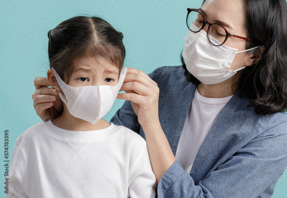 Mom and Asian little child girl is wearing medical face masks to protect themselves from pollution Coronavirus flu virus, New coronavirus 2019-nCoV from China, Empty space isolated on blue background