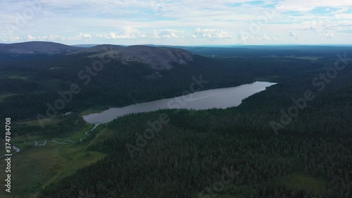 Aerial view tilting towards lake Kesankijarvi and the Kesanki fell, on a gloomy, summer day, in Pallas-Yllastunturi national park, Kolari, Lapland, Finland - reverse, drone shot photo