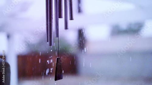Rain falling on wind chime tubes in slow motion, hand held shot in slow motion photo