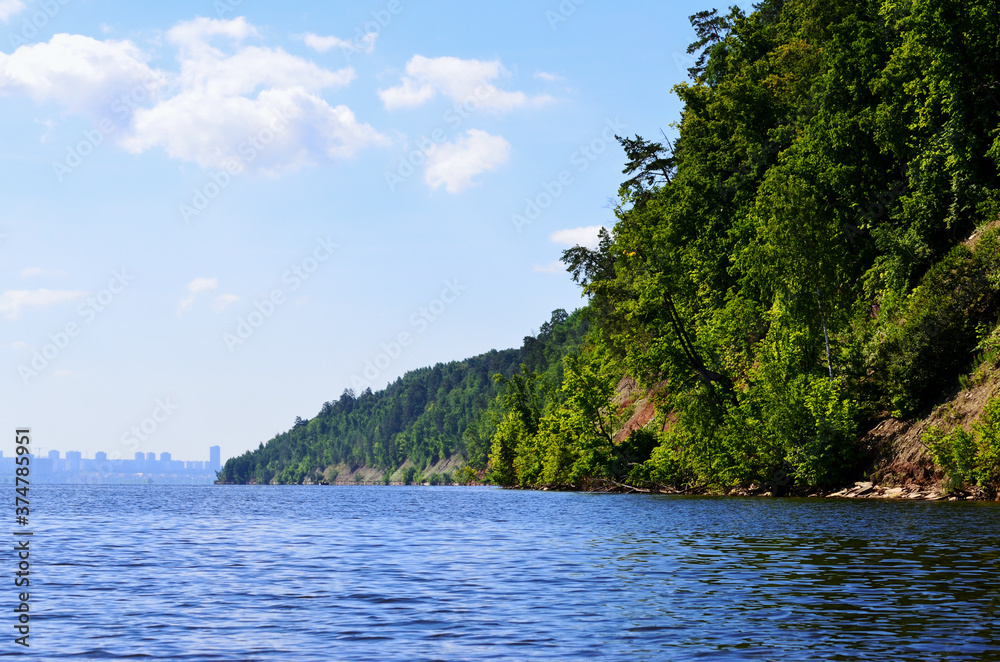 steep bank of the river overgrown with trees go into the distance