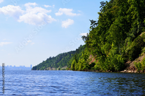 steep bank of the river overgrown with trees go into the distance © Svetlana