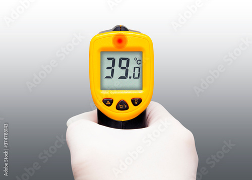 Hand holding a thermometer isolated on gray background. 
