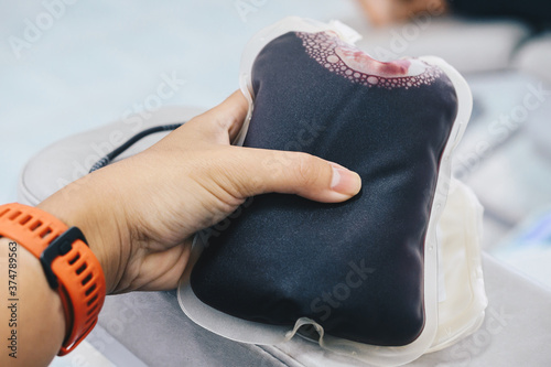 Volunteer holding a plastic blood bag after donate his blood for a community supply or to hospital.