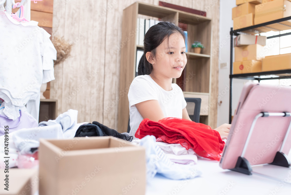 business child girl working online e-commerce shopping at her shop. kid seller prepare parcel box of product for deliver to customer. Online selling, e-commerce. doing business in her home.. business child girl working online e-commerce shopping at her shop. kid seller prepare parcel box of product for deliver to customer. Online selling, e-commerce. doing business in her home..