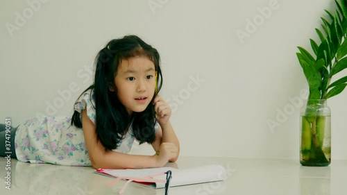asian child student or kid girl smile writing drawing and enjoy doing homework or happy read learn and training write on paper 