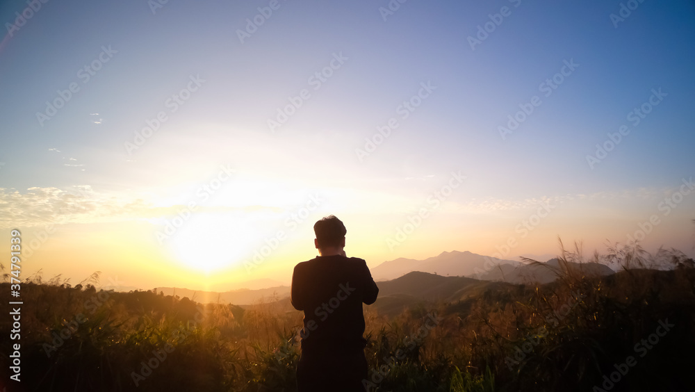 silhouette of young Asian tourist traveler man standing relaxing enjoying beautiful nature morning sunrise at Elephant Hills National Park (Noen Chang Suek) Thong Pha Phum, Kanchanaburi , Thailand