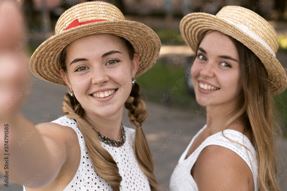two cheerful twin tourist girls take a selfie. Take a photo