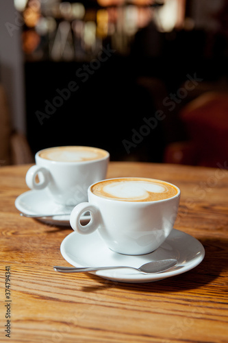 Two white cups of coffee with latte art. Morning in a cafe. 