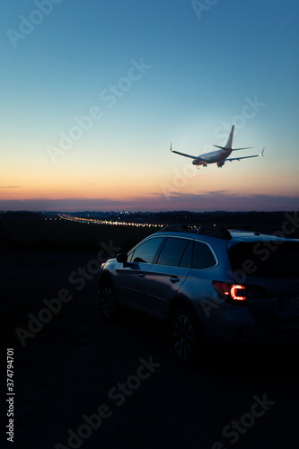 view of the car with taillights airplane landing on background