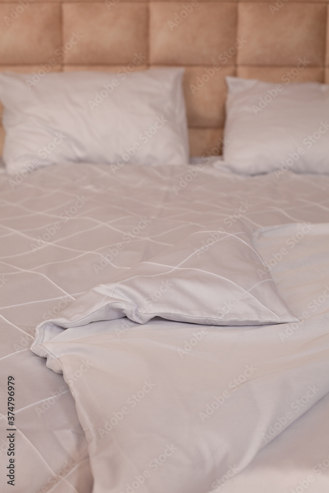 Unmade empty bed. White linens. Home comfort