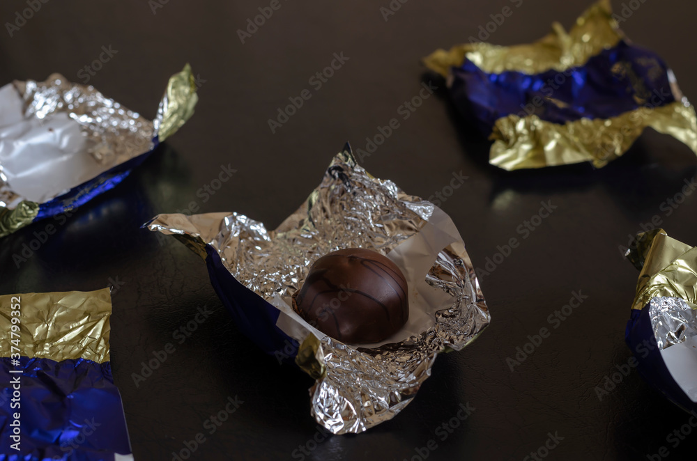 Single unwrapped chocolate bar among candy wrappers. Stock Photo ...
