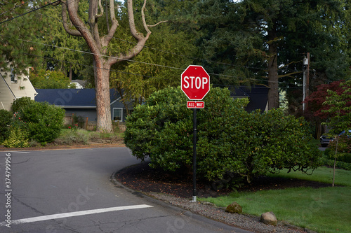 A quiet neighborhood street with all-way stop (also known as four-way stop) roadsigns.
