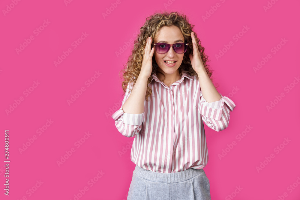A young woman holds her head with her hands with delight and joy A young woman holds her head with her hands with delight and joy