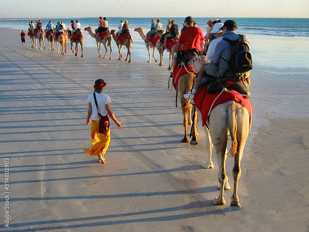Tourist taking a camel ride on Cable Beach at sunset, Broome - Australia