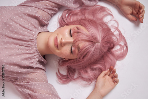 Portrait of a sexy young woman with pink hair. Perfect hairstyle and hair coloring. Girl with beautiful blue eyes and long pink hair