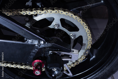 Motorcycle chain and sprocket on dark background.