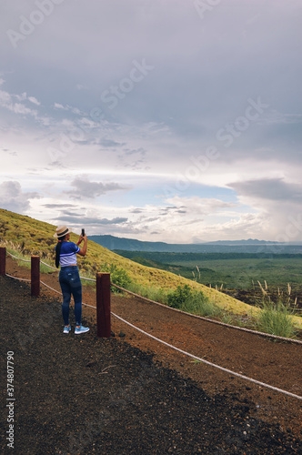 Young female taking pictures of landscape with smartphone at masaya volcano national park photo