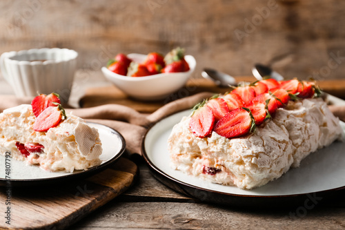 Delicious meringue roll with strawberry on table