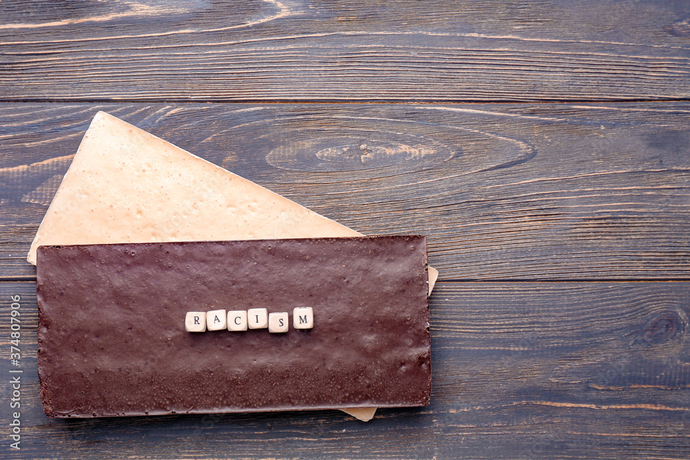 Chocolate bars with word RACISM on wooden background Chocolate bars with word RACISM on wooden background