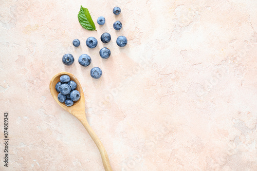 Spoon with tasty blueberry on light background