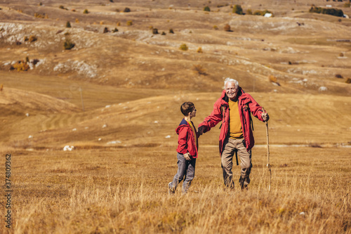 Senior man with grandson on country walk in autumn.