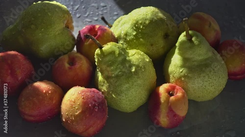 Juicy fruits pears and peaches on the table in sunlight and splashes of water photo