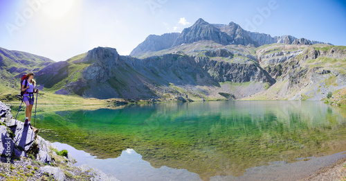 Young mountaineer girl next to the ibon of sabocos in the Pyrenees, Huesca. Reflection of mountains in the lake © marcos