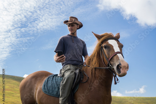 A rider in a wide-brimmed cowboy hat on a horse against a blue sky.