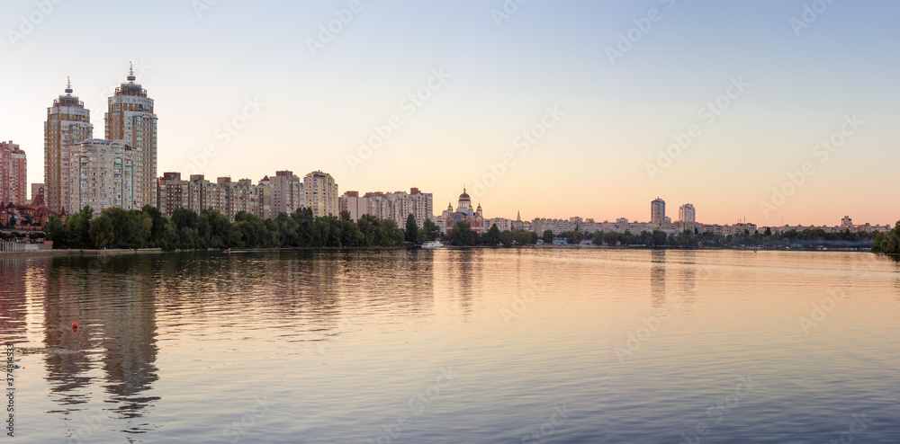Panorama of modern city with river on foreground after sunset