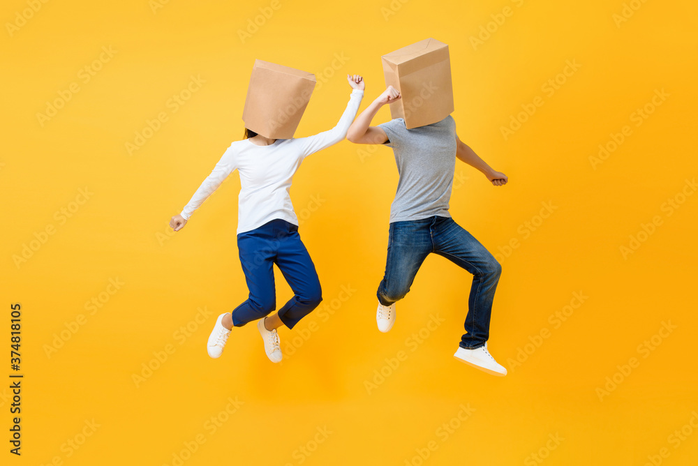 Φωτογραφία Fun portrait of faceless anonymous couple covering heads with paper bags jumping