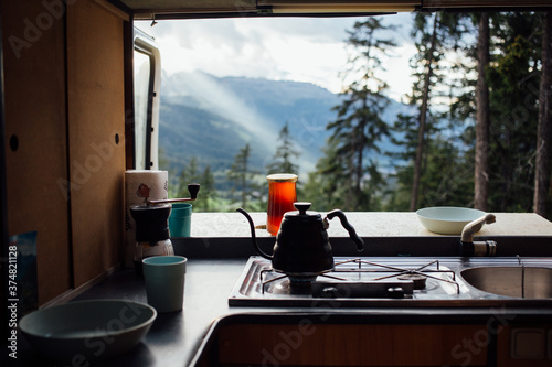 Interior of converted camper van or camping RV kitchen, coffee kettle and grinder stand on indoor table. Concept vanlife on the road, outdoor camp vibes for digital nomads