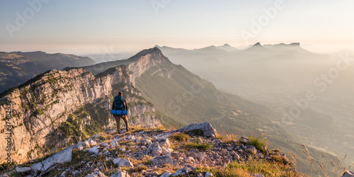 man standing face to the mountains during sunrise over grenoble photo
