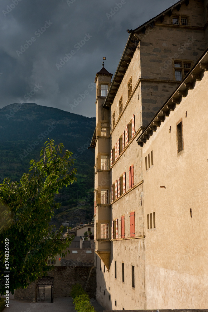 Last sunlight shining on the Stockalper Palace in Brig, Switzerland, in the background mountains and dark, threatening clouds