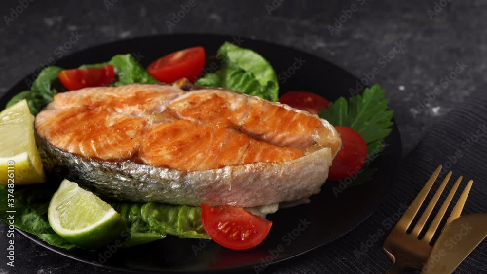 Prepared salmon steak with salad leaves in ablack plate. Macro shot of healthy food concept and dieting. Movement from right to left. 4K