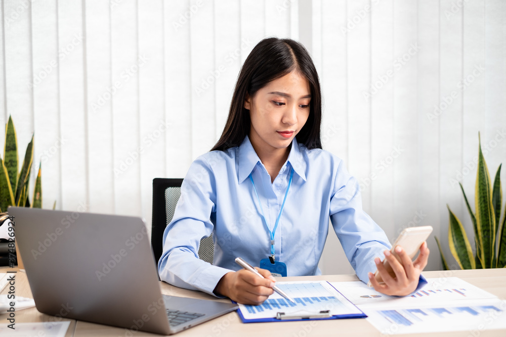 Asian women sit at their desks and calculate financial graphs showing results about their investments, plan a successful business growth process Asian women sit at their desks and calculate financial graphs showing results about their investments, plan a successful business growth process