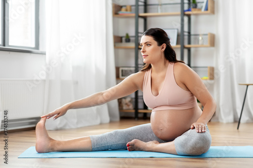 sport, fitness and pregnancy concept - happy pregnant woman doing sports at home