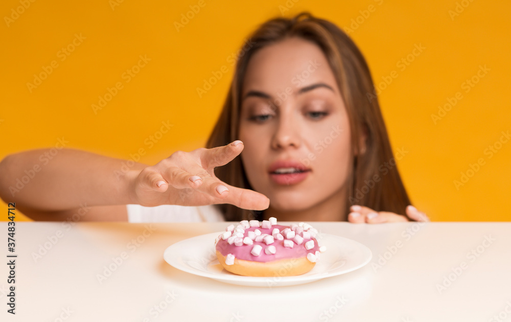 Woman peeking out of table and taking sweet delicious donut Woman peeking out of table and taking sweet delicious donut